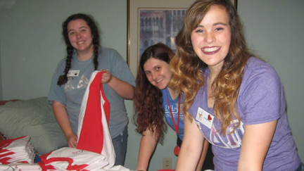 Three young women unpacking Ronald McDonald House shirts